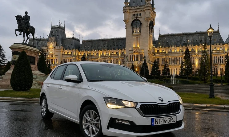 Mașină de închiriat Škoda Scala albă, fotografiată în fața Palatului Culturii din Iași, la apus.